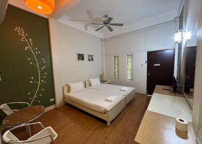 Modern bedroom with twin beds, wooden floor, and greenery-themed wall decor