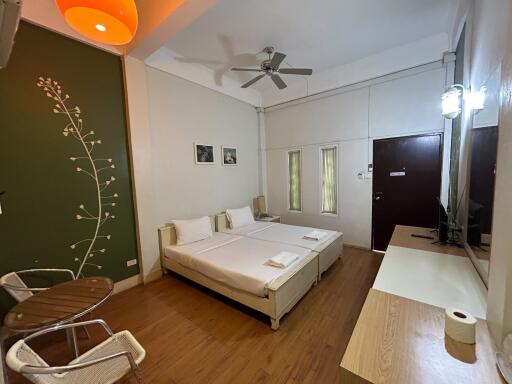 Modern bedroom with twin beds, wooden floor, and greenery-themed wall decor