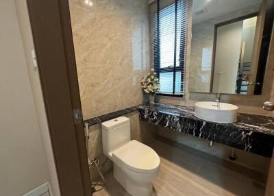 Modern bathroom with marble walls, a countertop sink, and a toilet