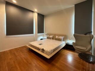 Modern bedroom with hardwood floors and large windows.