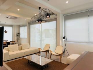 Modern living room with white sofas, minimalist chairs, coffee table, and contemporary lighting fixtures