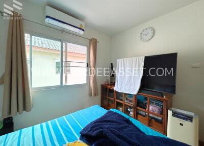 Bedroom with air conditioner, window, brown curtains, a clock, and a wooden cabinet