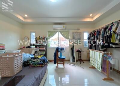 Spacious bedroom with ample storage, clothing racks and a bright window