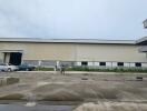 Exterior view of a large warehouse with vehicles