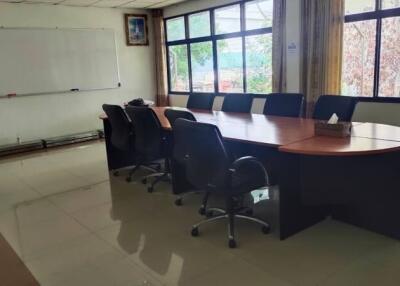 A conference room with an oval table and chairs around it.