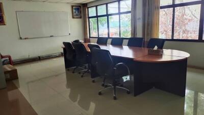 A conference room with an oval table and chairs around it.