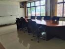 A conference room with an oval table and chairs around it.