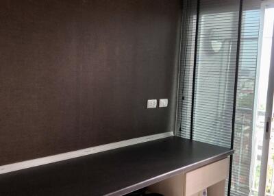 A work desk with shelves adjacent to a window with blinds