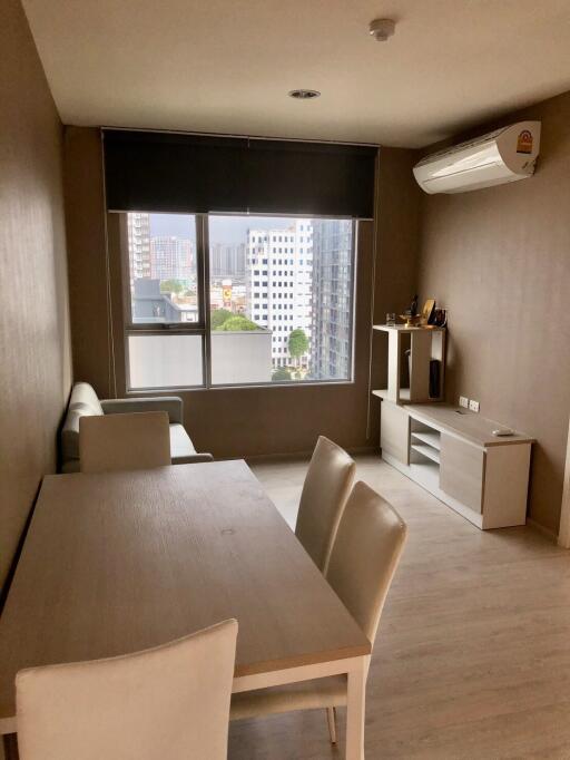 Modern living room with dining table, sofa, air conditioner, and city view window