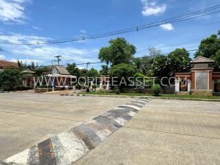 Outdoor area with a paved road, greenery, and decorative structures