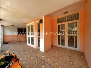 Covered outdoor patio with tiled flooring and large glass doors and windows