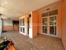 Covered outdoor patio with tiled flooring and large glass doors and windows