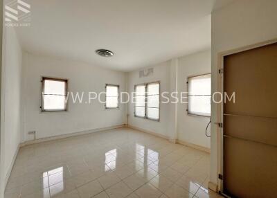 Spacious empty living room with tiled flooring and multiple windows