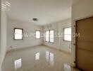 Spacious empty living room with tiled flooring and multiple windows