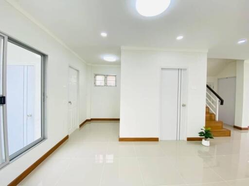 Spacious clean modern apartment interior with white walls, tile flooring, and staircase