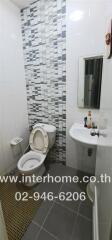 Modern bathroom with toilet, sink, and decorative wall tiles