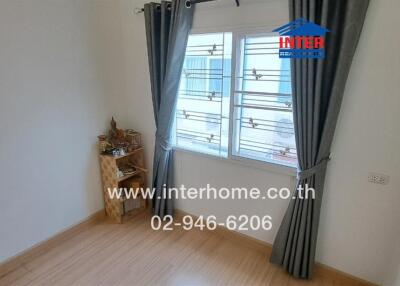 Cozy bedroom with wooden flooring and a window with curtains