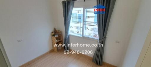 Cozy bedroom with wooden flooring and a window with curtains