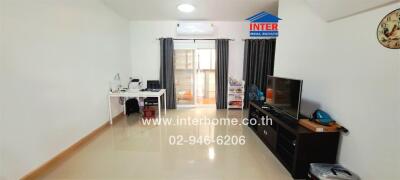 Modern living room with TV, desk, and sliding door to balcony