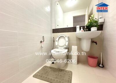 Bathroom with sink, toilet, large mirror, and decorative plants