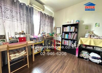 A cozy and well-organized bedroom with bookshelves, a desk, and an air conditioning unit