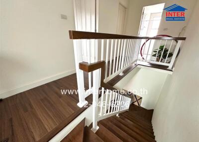 Interior view of a staircase with wooden steps and white railings