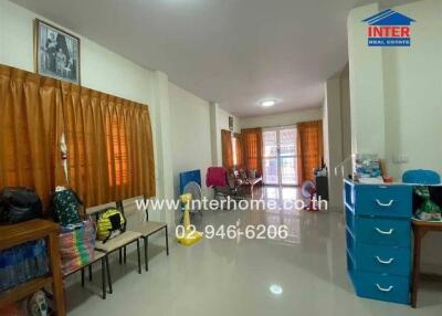 Spacious living area with window curtains, chairs, fan, and storage drawers