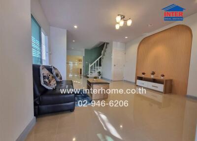 A spacious and modern living room with a staircase, seating area, and decorative elements