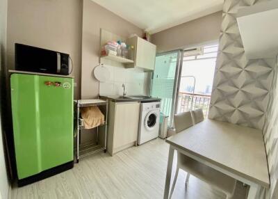 Modern compact kitchen with bright green refrigerator, washing machine, and dining area