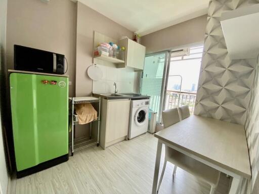 Modern compact kitchen with bright green refrigerator, washing machine, and dining area