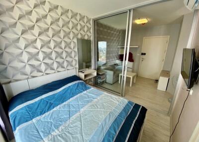 Modern bedroom with geometric wallpaper, large mirror, sliding glass door, and blue bedspread