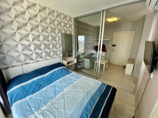 Modern bedroom with geometric wallpaper, large mirror, sliding glass door, and blue bedspread