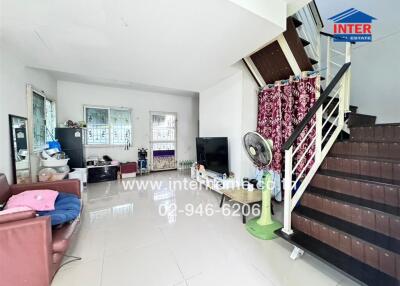 Living room with modern decor, TV, sofa, and staircase