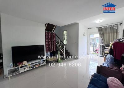 Living room with large TV, staircase, and balcony access