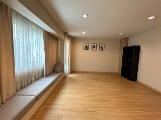 Spacious living room with wooden floors, large window, and built-in seating