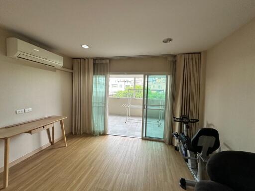 Living room with wooden floor, large window, and balcony