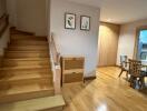 Stairway leading to living area with wooden floors and dining table