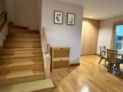 Stairway leading to living area with wooden floors and dining table