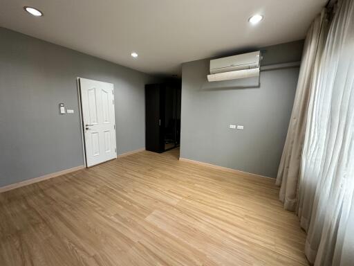 Spacious bedroom with wooden flooring and air conditioning