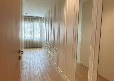 Long hallway with wooden flooring and built-in closets with mirrors