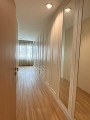 Long hallway with wooden flooring and built-in closets with mirrors