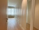 Long hallway with wooden flooring and built-in closets with mirrors