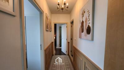 Hallway with wall art, chandelier, and doorways