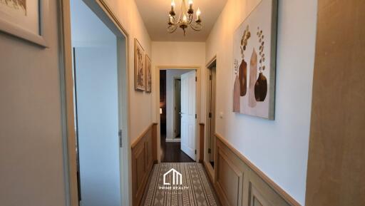 Hallway with wall art, chandelier, and doorways