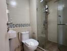 Modern bathroom with glass-enclosed shower, toilet, and wall-mounted sink