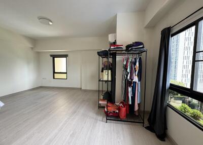 Spacious bedroom with large windows and clothing rack