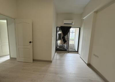 Empty bedroom with hardwood floor, open door, window with sliding glass door, and air conditioning unit