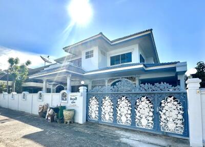 Front view of a spacious two-story house with decorative gate and sunny weather