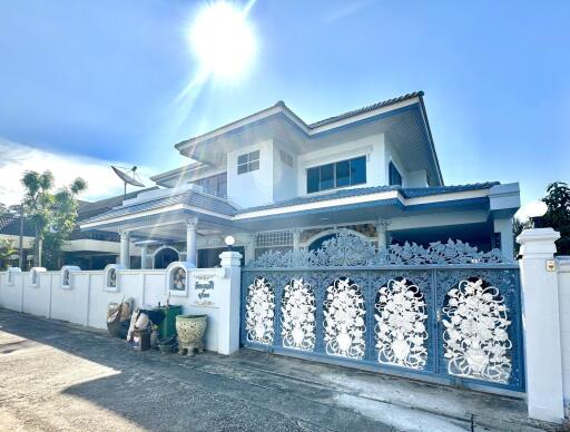 Front view of a spacious two-story house with decorative gate and sunny weather