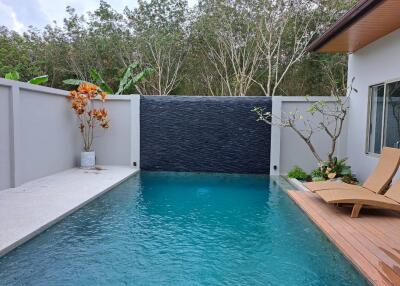 Outdoor pool area with lounge chairs and private wall